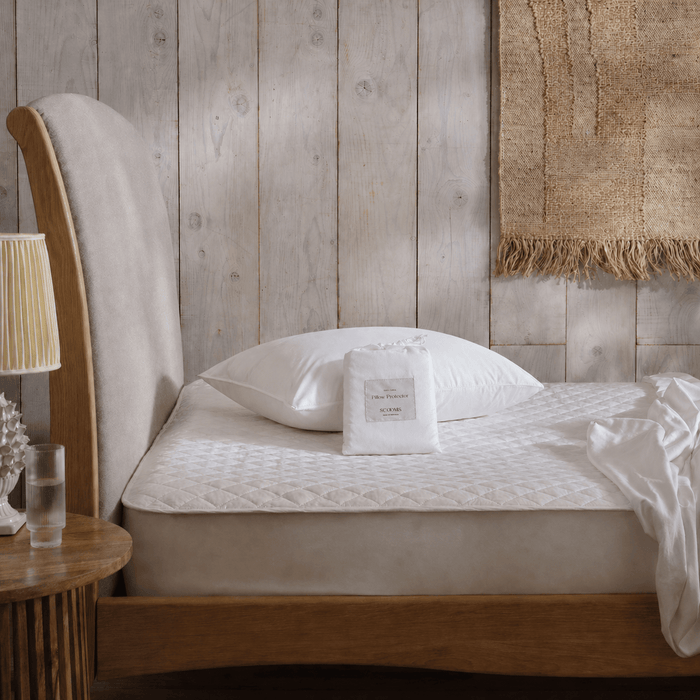 Pillow covered with cotton pillow protector and protector in bag on unmade bed | Scooms