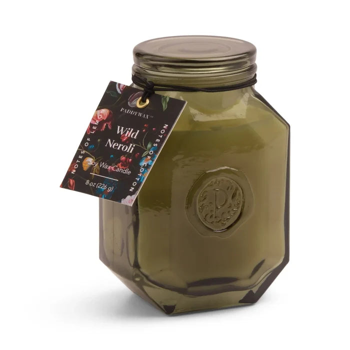 The 8oz Botanica Candle is a green octagonal glass jar with a black lid, decorative Wild Neroli tag, and embossed logo for elegance—a luxurious addition to the Botanica Collection.