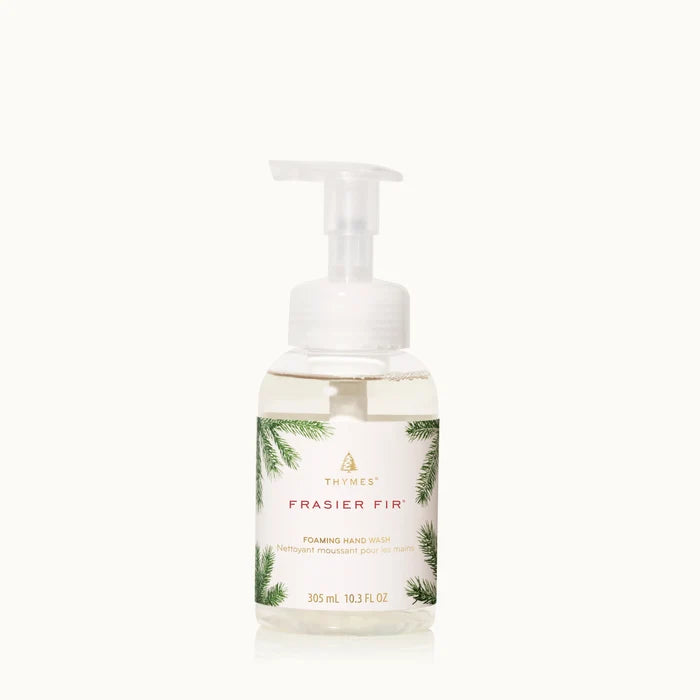 A clear pump bottle of Frasier Fir Home Care Collection foaming hand wash features a white label with pine branch art and gold text. The 305 mL (10.3 fl oz) pale yellow liquid offers a refreshing winter scent.