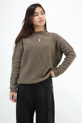 A woman modeling a brown knit sweater with a relaxed fit, paired with black pants, against a plain white background.