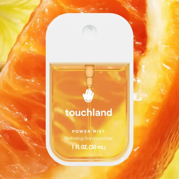 A bottle of Touchland Hand Sanitizer Mist with orange liquid is shown against a close-up juicy orange slice background, keeping your hands clean and hydrated.