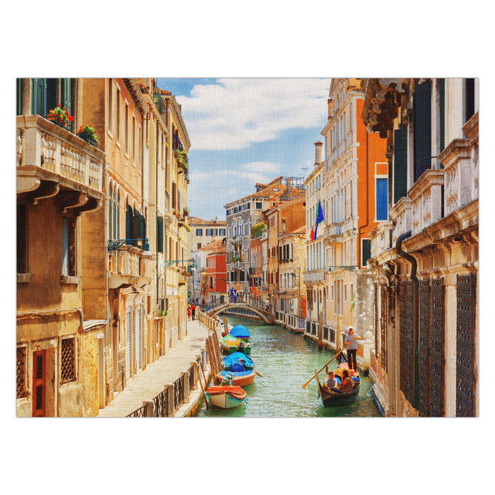 A colorful linen placemat featuring a vibrant print of a canal in Venice with boats and buildings on either side.