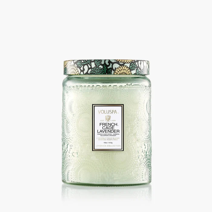The Voluspa 18oz Glass Jar Candle features clean-burning coconut wax in an embossed glass jar with a floral-embellished lid, perfectly complementing the white candle inside.